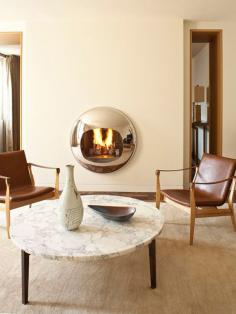 A polished bubble of a fireplace doubles as sculpture in this Paris apartment designed by Pierre Yovanovitch. Photo by Lux Productions.