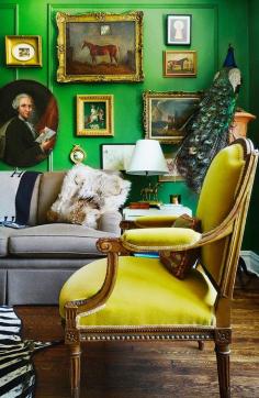 Mustard mohair chair in green living room with gallery wall of portraits and paintings.