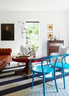 
                    
                        A bright space with a cottage feel gets a double dose of tension: bright blue chairs and a striped rug laid at an unexpected angle.
                    
                