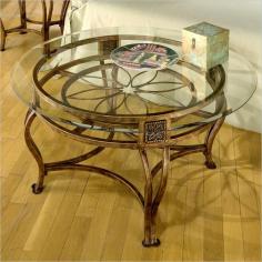 Enjoy the beauty of a themed cocktail table from above or from the sides. A floral motif is crafted with intricate wrought iron shaping at the hub of the frame. Apron features matching artisan crafted insets topping the bowed legs. * For residential use. This exquisite table features graceful flowing lines and intricate castings. The most stunning effect, however, is the flower motif and lovely brown rust finish that lies beneath the clear glass top. Brown rust finish. Floral motif. Some assembly may be required. Table: 28 in. W x 17.5 in. H x 28 in. D. Glass Top Diameter: 39 in.