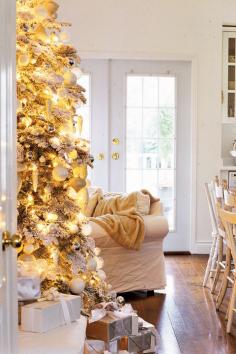 An all-white home becomes a holiday haven with glittery decorations and a shimmering gold tree.