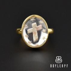 Beautiful  hand-painted cross surrounded by stars is artfully carved in this antique Victorian Essex crystal ring rendered in 18K gold. The domed rock crystal is set in a gold collet mounting joined to a simple band. The rock crystal is backed with foil to give incredible reflection with the stars painted in a silvery color and the cross in a pink and white. When viewing from the side, you can see the carving which is expertly carved.