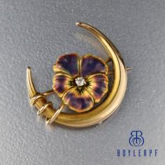 Rendered in a heavy 14K yellow gold with a vibrant brilliant diamond center, an enamel pansy flower sits within a crescent moon in this Art Nouveau brooch watch pin. A 2.5mm sparkling diamond rests in the center of curving purple and gold enamel pansy petals with detailed accents. 