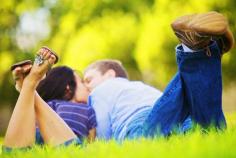 Cute couple pose kissing in grass.