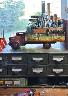 vintage metal toy trucks with an old cigar box in the bed and a wire test tube rack tucked inside of that. This set-up holds items upright that I such as small clamps, rulers, scissors, craft knives, Sharpies and more.