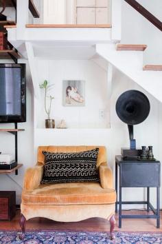 Apricot lounge chair with mudcloth pillow under staircase.