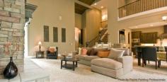 Contemporary family room with a simple warm design, a long wrought iron railing across the second story, beige carpeted flooring and a stone fireplace. Click on the pin to our favorite fireplace designs.