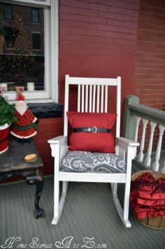 Christmas porch decor - I think my favorite part is the red pillow with the belt on it.  I would never have thought of that.