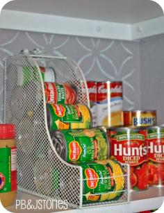 Magazine racks in the pantry. It's the PERFECT size to hold our little cans of veggies!  The two little stoppers are bobby pins flattened and spray painted white. FYI: This a magazine holder was originally purchased from HomeGoods.  Cans are not traditional size, they are the "little" cans that are about half the size of regular cans.