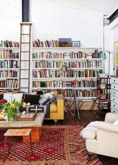 wall of open book shelves, eclectic living space.  stunning personal library (via The Design Files)
