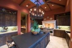 
                    
                        Kitchen with cathedral ceiling painted red highlighting large dark island in the center of dark brown cabinets and stainless steel appliances
                    
                