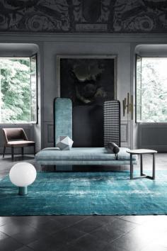 The blue turquoise rug gives depth to the living room. The golden wall lamp is a amazing detail