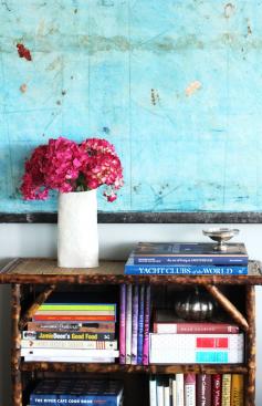 Contrasting colors make for a visually stunning effect. You just can't stop staring at those vibrant pink flowers against the blue painting!  Plus, the bamboo bookcase that she found at a flea market is such a distinct touch.