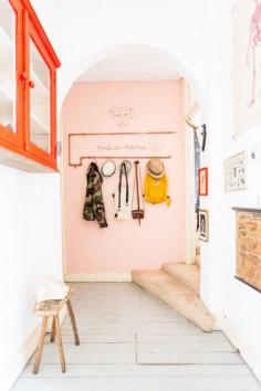 Pale pink wall in the hallway, orange cupboard, quirky art
