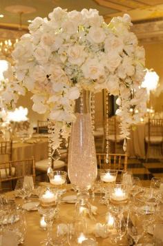 
                    
                        This grand centerpiece is a definite crowd pleaser, the tall vase is filled with crystals and accented by crystal strands dripping from an arrangement of roses, hydrangeas and orchids.
                    
                