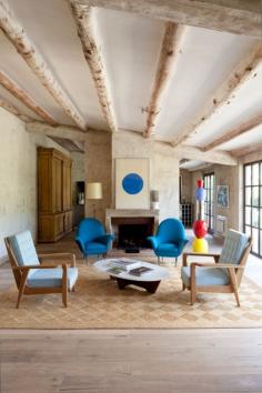 House tour: an interior designers' home with a constantly rotating collection of antiques and objets d'art : For example, in the same living room as previously pictured, two Scandinavian rosewood framed blue cushioned chairs and two royal blue lounge chairs from the 1950s, compliment the blue gouache of an Albert Chubac artwork. The colourful totem is by Alessandro Mendni.