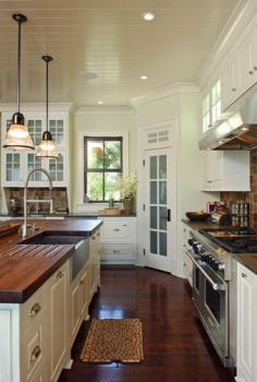 Bead board ceiling and dark hardwood in kitchen, White cabinets with butcher block countertops & the sink! I love the pantry door, that way you can look for something without opening the door :)