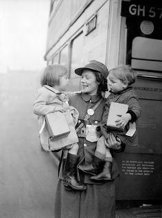 
                    
                        A bus conductress holds two young evacuees who are being taken by bus to a safer part of the country during a London County Council scheme during World War II.
                    
                