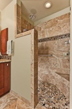 The traditional shower has been removed and this beautiful walk-in open shower with seat, stone flooring, tile walls, mosaic band, and beaut...