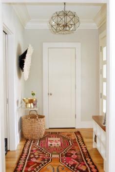 Entryway with patterned red and pink kilim rug and woven basket