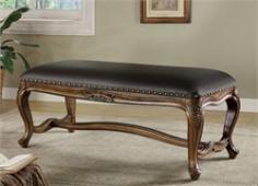 A leather like black vinyl contrasts beautifully with the traditionally styled base of this upholstered bench. A center stretcher binds the base together and echoes the classic curves of the bench's legs. The generously proportioned bench seat is upholstered in a subtle and durable black vinyl that recreates the luxurious look of leather. Individually placed brass colored nail heads trim the seat for a tailored look. A medium golden finish bathes the base, accentuating the carved floral motif featured on the cabriole legs.
