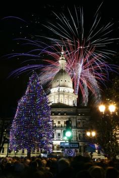 Fireworks explode over the state Capitol following a ceremony lighting the official state Christmas tree in Lansing, Michigan. (Photo by Al ...