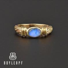 The blue opal doublet is front and center in this vintage 14K gold band ring. The opal flashes electric colors of blue with vivid green, purple and pink throughout. the thick band has a twisted design that graduats to the back. 