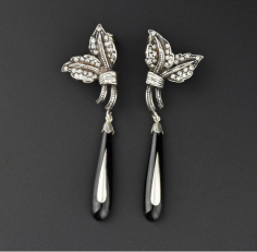 Beautiful long dangling black teardrop-shaped pendants of black onyx with sterling silver diamond-like paste studded flowers at the top form these fashion-forward antique Art Deco earrings. The graduated pendants which have a sterling silver overlay, sway from leaf shapes with post backs for pierced ears. The earrings are the perfect chic accessory for the LBD.